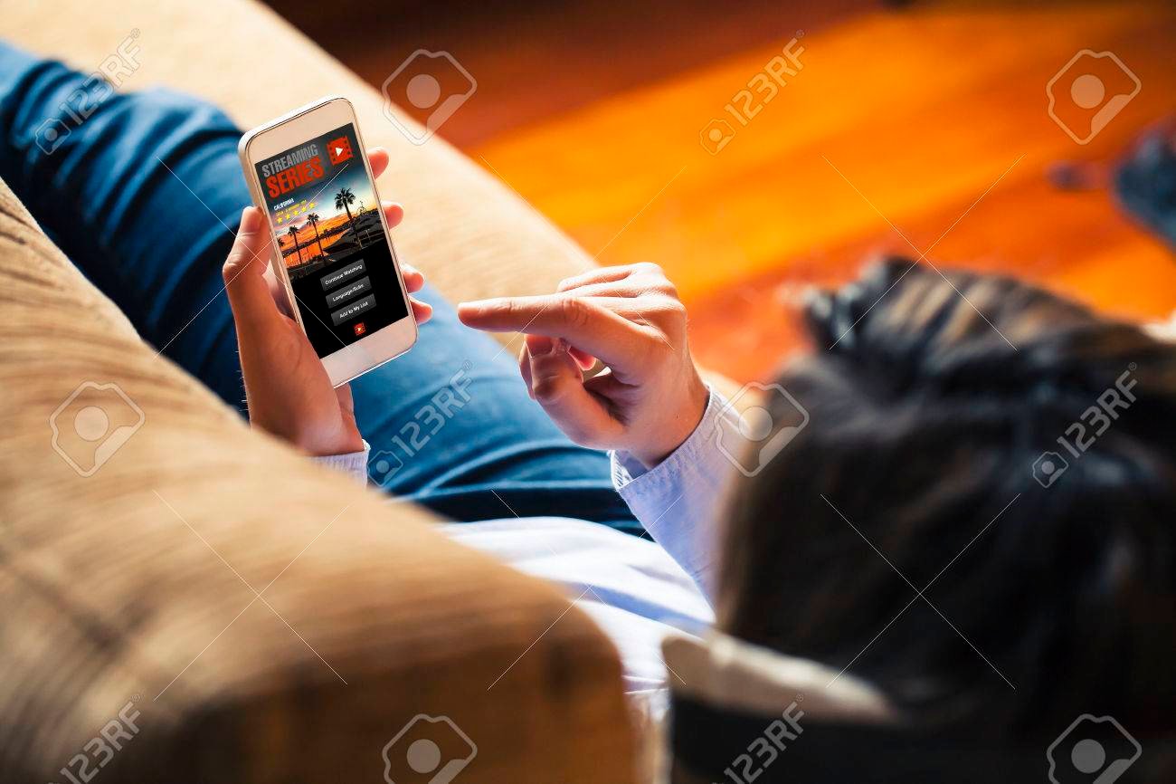 79820797 mujer viendo series de television en una aplicacion de telefono movil mientras que el resto en