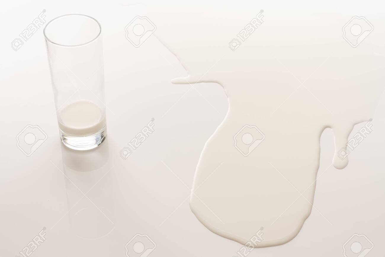 vaso de leche derramado en mesa blanca