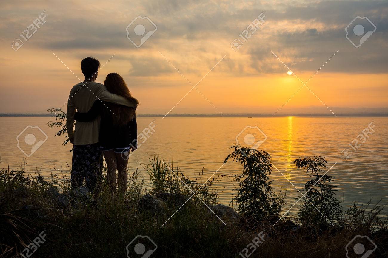 pareja abrazada frente a un atardecer